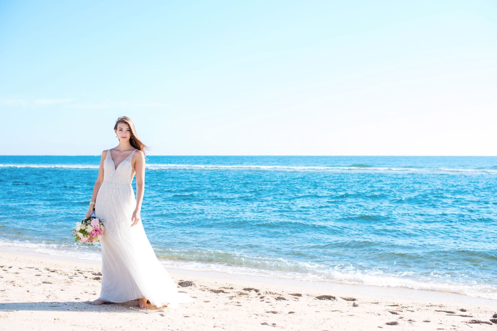 brunette bride wearing white wedding dress on seashore