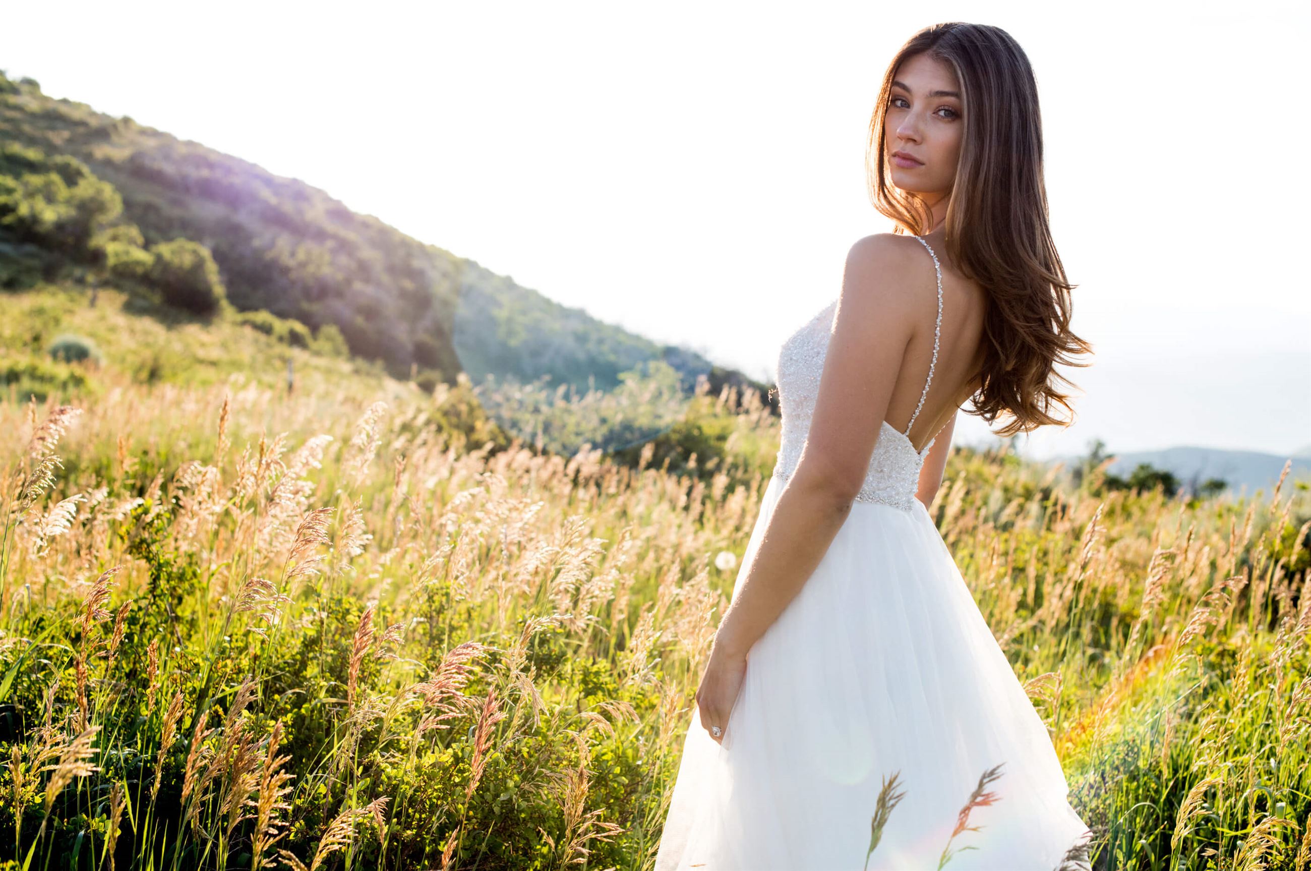 Brunette model in white wedding dress in field